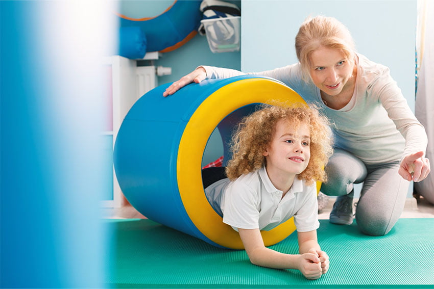 Ein Kind kriecht durch einen tunnel und nimmt somit an dem Kurs Bwwegungsförderung für Kinder teil