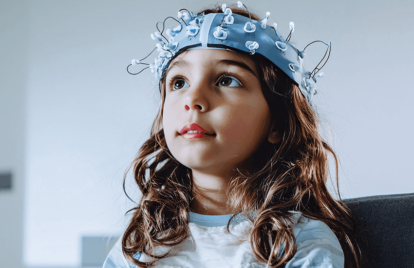 Kind sitzt ruhig und trägt eine Kappe mit mehreren Elektroden zur Messung der Gehirnaktivität